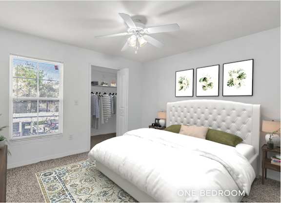 A bedroom with a large bed, a ceiling fan, and a window with a view of trees.