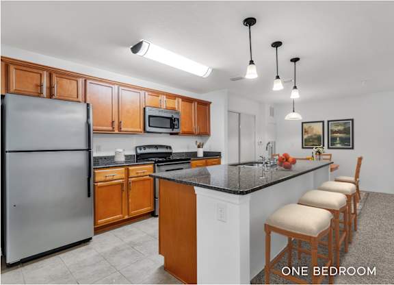 A kitchen with a refrigerator, microwave, and stove top oven.