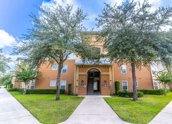a building with a sidewalk and trees in front of it