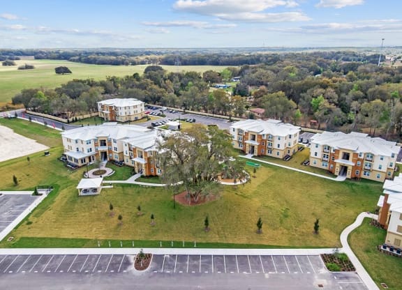 an aerial view of an apartment complex with a field and trees