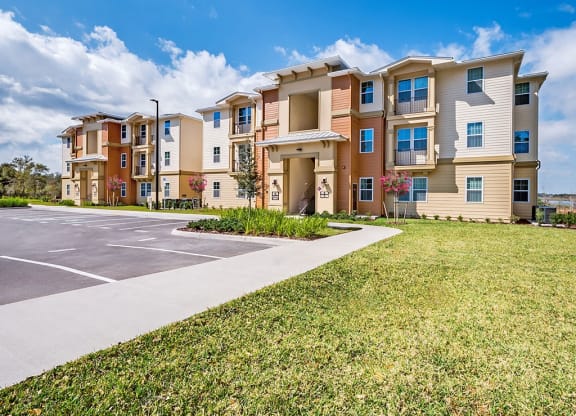 an apartment building with a parking lot and grass