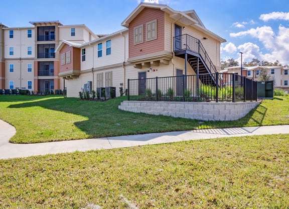 an apartment building with a lawn and sidewalk in front of it