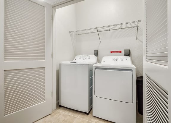a laundry room with two washer and dryers next to a door