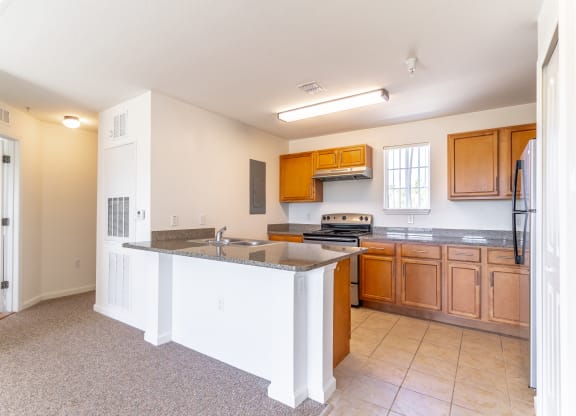 a kitchen with an island with granite countertops and wooden cabinets
