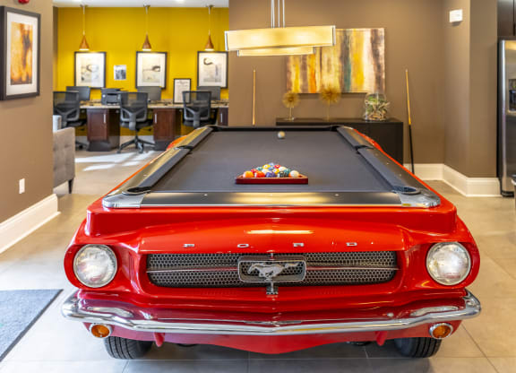 a pool table with a red car in the middle of the room
