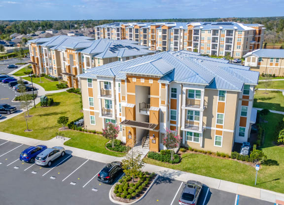 an aerial view of a large apartment complex with cars parked in front of it