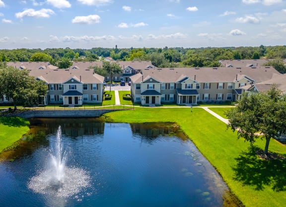 a fountain in the middle of a pond with houses in the background
