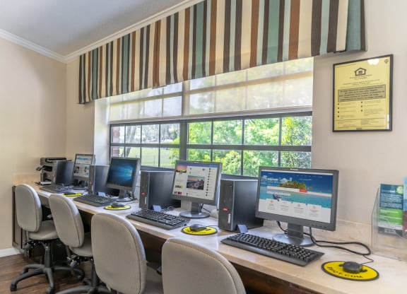 a computer lab with four computers and a row of chairs