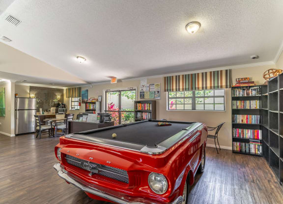 a game room with a pool table and bookshelves