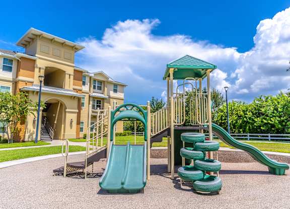 A playground with a green slide and a wooden structure.