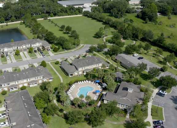 A bird's eye view of a residential area with houses, a swimming pool, and a pond.