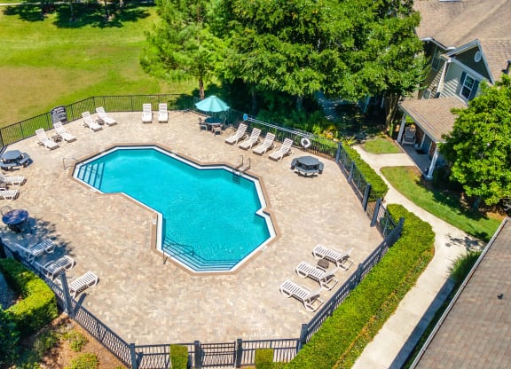 an aerial view of a large pool with lounge chairs and trees in the background