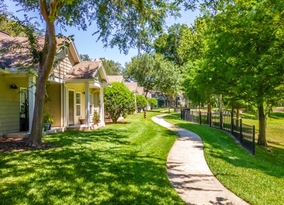 a pathway through a park with cottages on either side