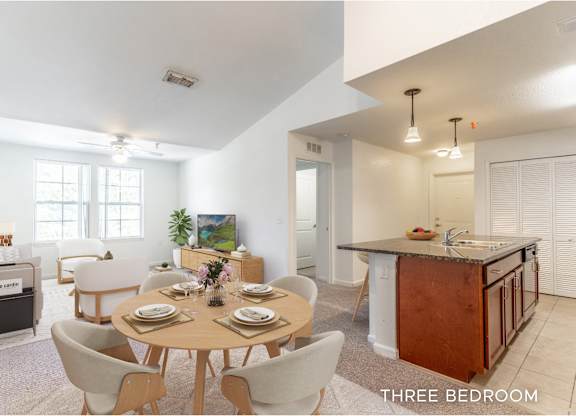 A well-lit, spacious kitchen and dining area in a three-bedroom apartment.