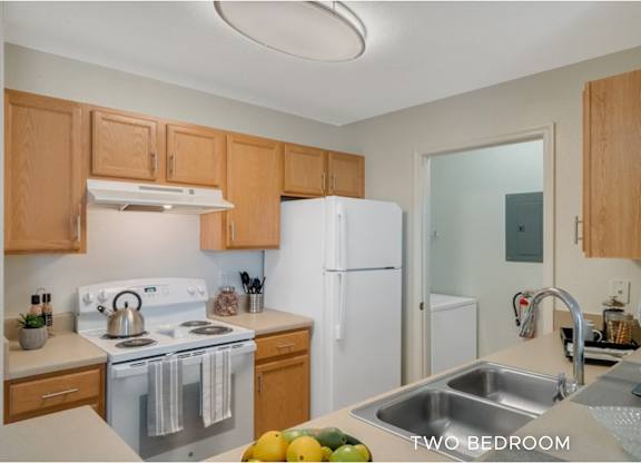 A kitchen with a stove, refrigerator, and sink.