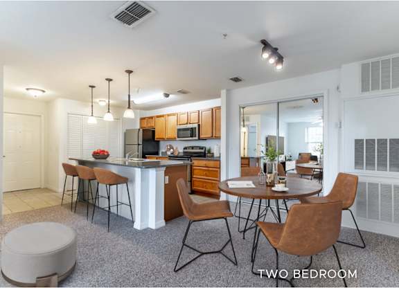 A modern kitchen with a bar area and a dining table with chairs.