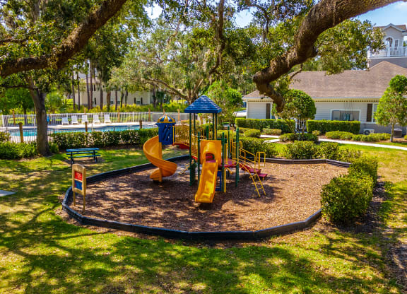 a playground with a slide and monkey bars in the middle of a grassy area with trees