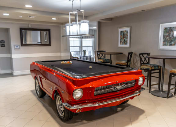 a pool table with a red car in the middle of the room