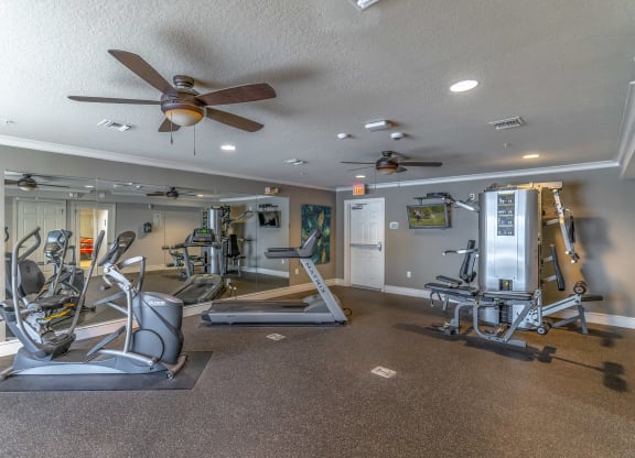 a gym with exercise equipment and a ceiling fan