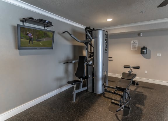 a gym with a treadmill and a tv on the wall