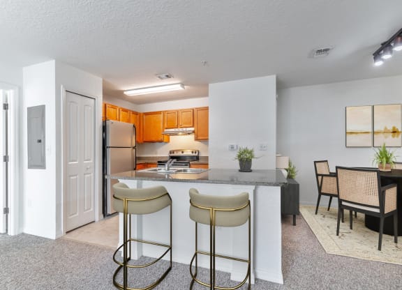 a kitchen with a breakfast bar and a dining room in the background