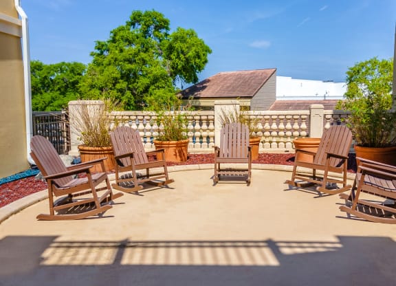 a circular patio with adirondack chairs and potted plants