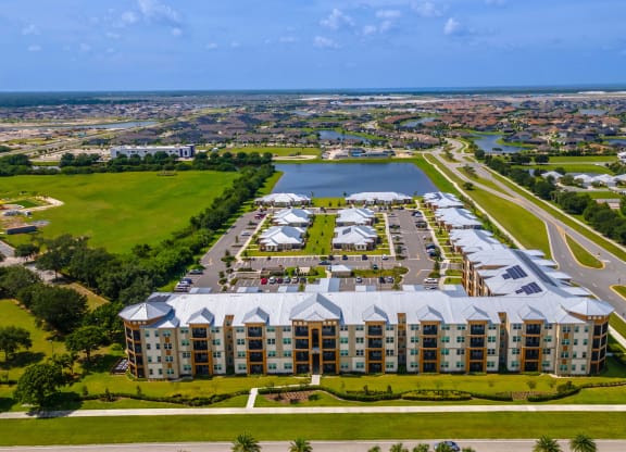 an aerial view of an apartment complex with a body of water and a city in the background