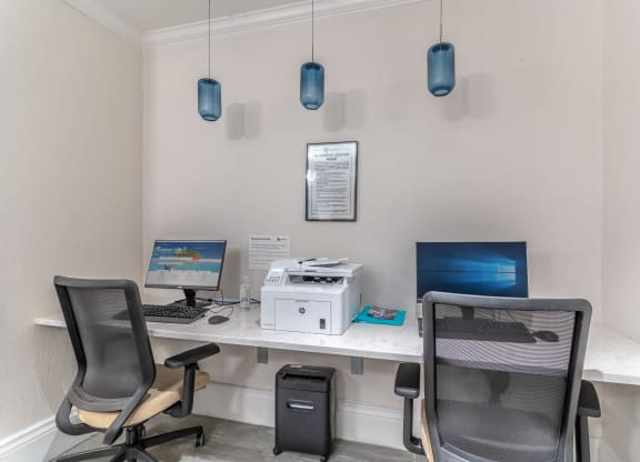 two desks with two computers and two chairs in an office