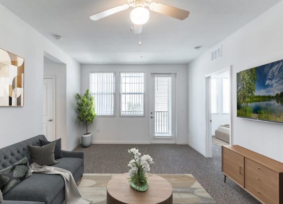 a living room with white walls and a ceiling fan