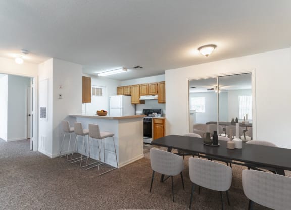 a dining area with a table and chairs and a kitchen in the background