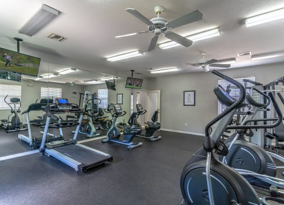 a gym with cardio equipment and a flat screen tv
