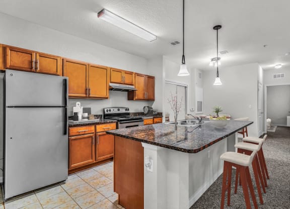 a kitchen with a large island with granite countertops and wooden cabinets