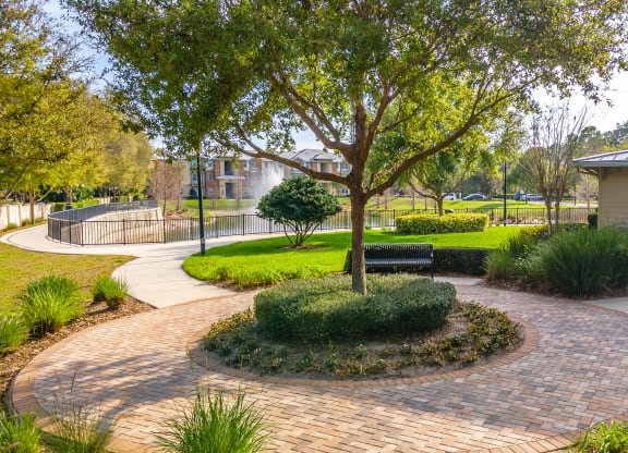 a circular brick walkway with a bench and tree in the middle of it