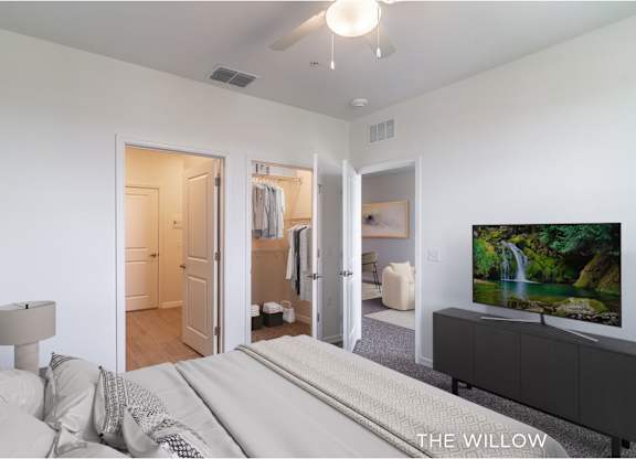 A bedroom with a large bed and a flat screen TV mounted on the wall.