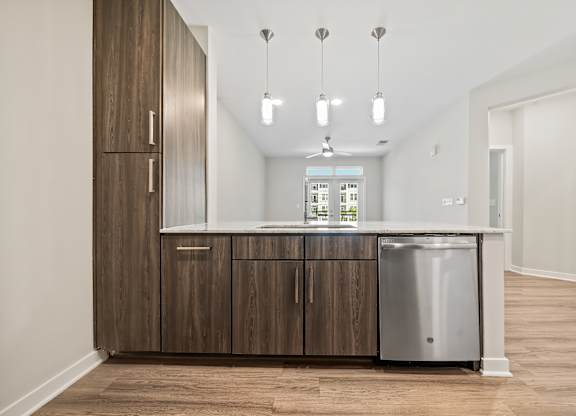 A kitchen with wooden cabinets and a stainless steel dishwasher.