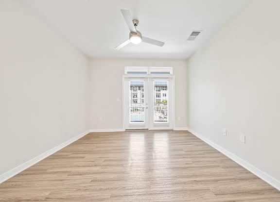 A room with a ceiling fan and wooden flooring.