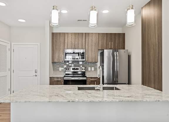 A modern kitchen with a marble countertop and stainless steel appliances.