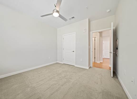 A room with a ceiling fan and carpeted floor.