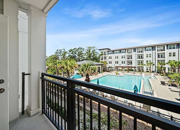 A balcony view of a pool and apartment building.