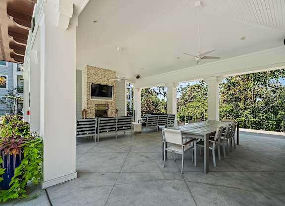 A patio with a table and chairs and a ceiling fan.