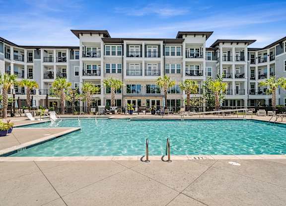 A large swimming pool in front of a multi-story apartment building.