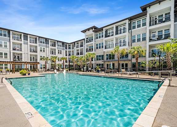 A large swimming pool in front of a multi-story apartment building.