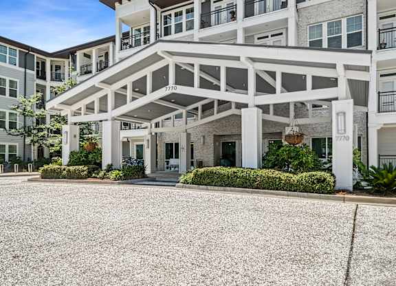 A large white building with a balcony and a covered walkway.
