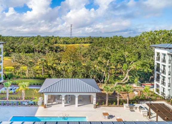 A swimming pool is surrounded by a building and a gazebo.
