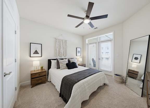 Carpeted bedroom with a ceiling fan, two nightstands, a tall leaning floor mirror, and a balcony door with blinds.