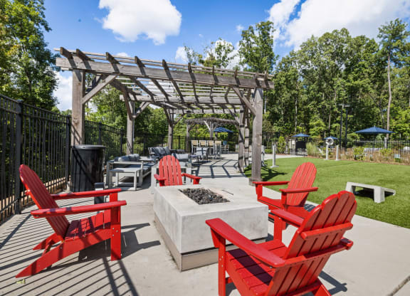 an outdoor patio with red chairs and a firepit