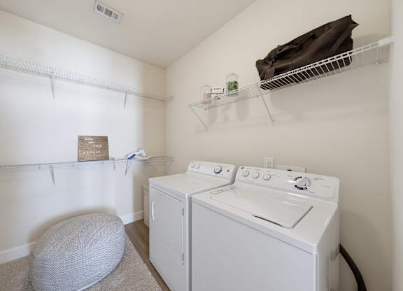 Laundry room with a side-by-side washer and dryer, wire shelving on three walls, and an overhead rack for storage.