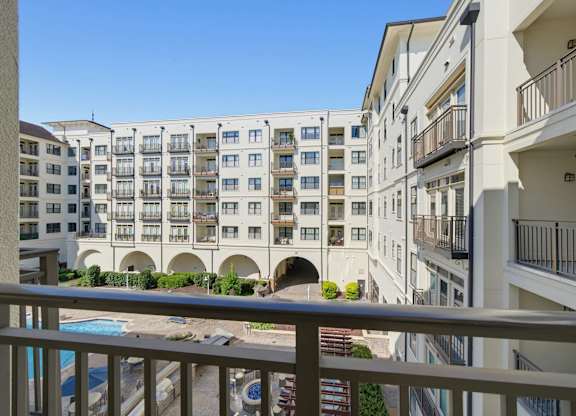 View from a private balcony over the courtyard, with the pool below and balconies across the facing building wing.