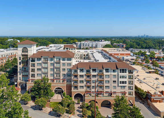 Aerial view of The Clark at Village District, its tile roofs and balconies set among Raleigh retail and tree canopy.