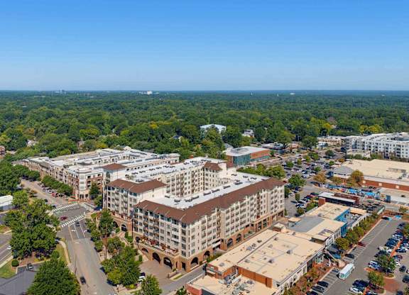 Wide aerial showing the apartment community at the center of the Village District, framed by streets and tree cover.